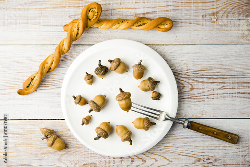 Canvas Print Acorns in a plate, bread and fork on the table
