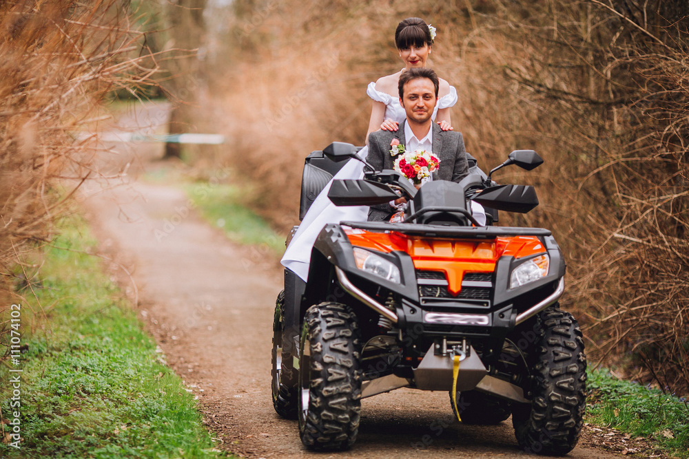 Happy beautiful couple driving four-wheelers ATV on forest road Happy beautiful couple driving four-wheelers ATV on forest road