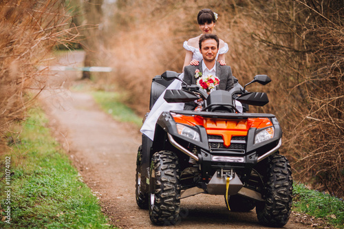 Happy beautiful couple driving four-wheelers ATV on forest road © nataliakabliuk