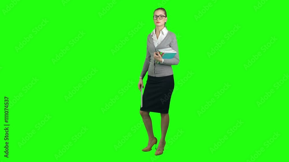 Serious young woman teacher standing on green screen background, holding books and ruler and looking at camera Serious young woman teacher standing on green screen background, holding books and ruler and looking at camera