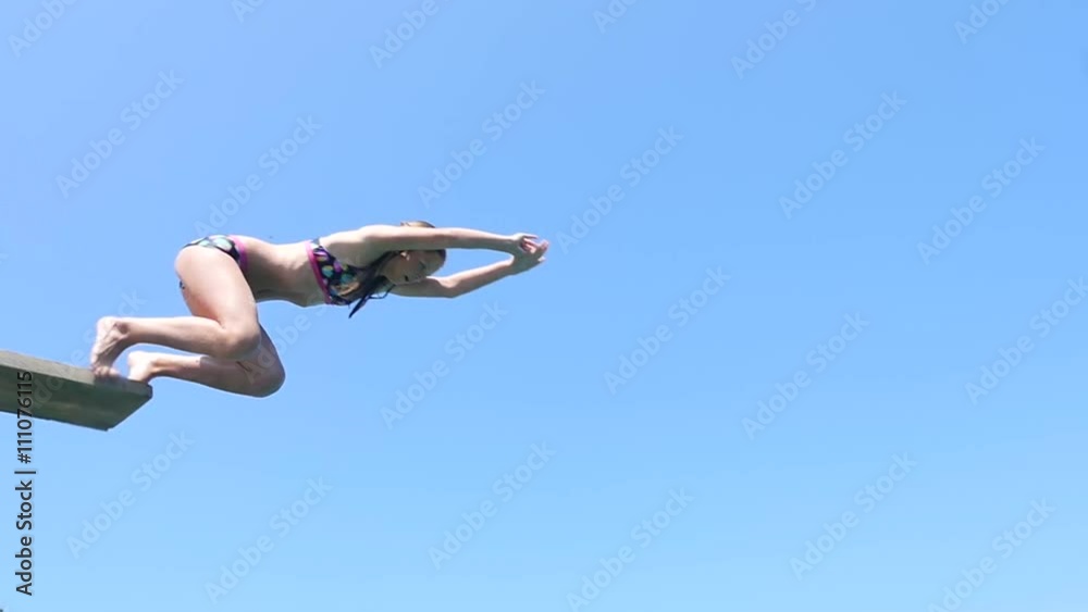 Playful teenage girl takes header jump from the springboard into sea water.
Playful teenage girl takes header jump from the springboard into sea water.