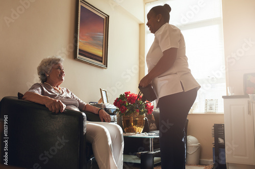 Senior woman at home with female caregiver photo