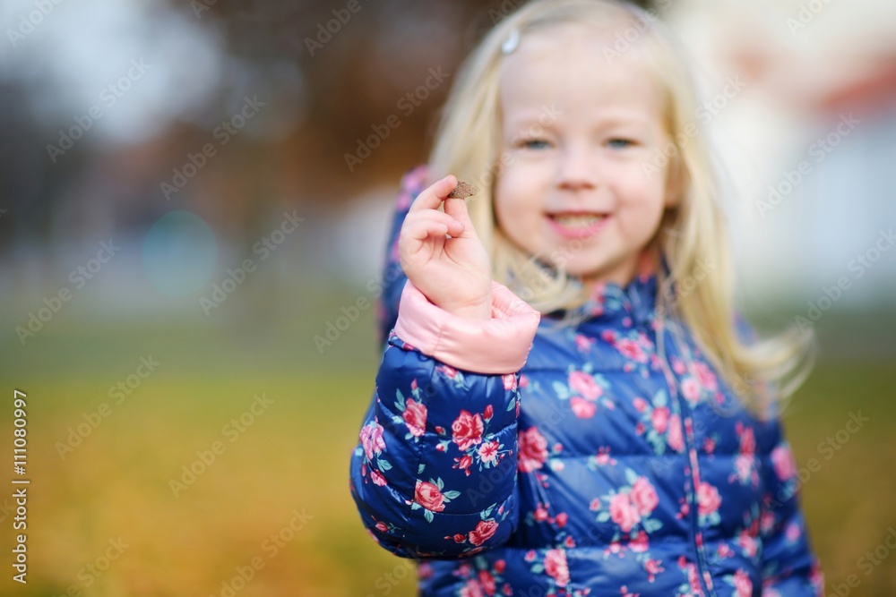 Little girl gathering acorns for crafting and playing on beautiful autumn day Little girl gathering acorns for crafting and playing on beautiful autumn day