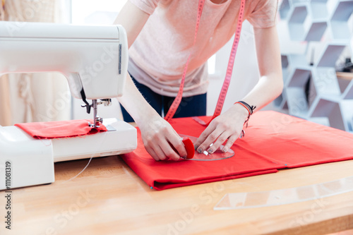Woman seamstress working making pattern on red fabric