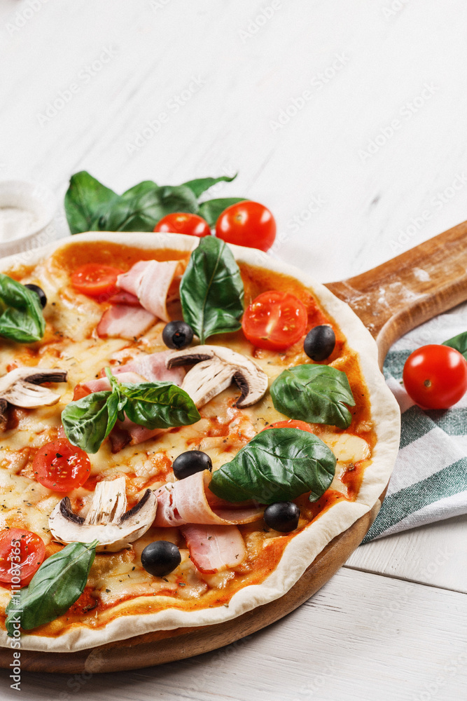 Close-up view of Italian PIZZA with mushrooms, basil, tomato, olives and cheese and bacon. WITHOUT one piece.  white wooden table background. Look as Prosciutto, Capricciosa, Funghi, Cotto PIZZA. 