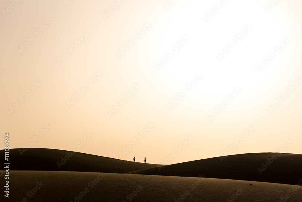 Couple walking  in desert with sunset on island gran canaria, spain
