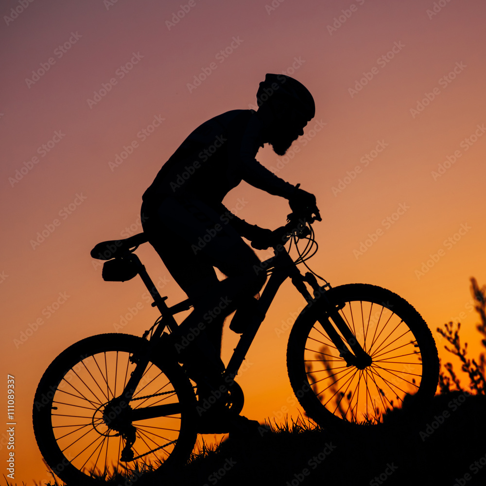 Fototapeta premium the young man riding a bike at sunset