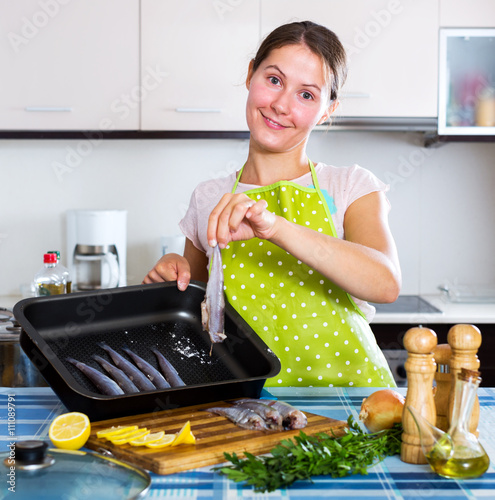 Woman putting sprats in baking photo