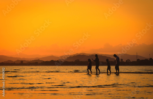 Silhouette of family on the beach at sunset.