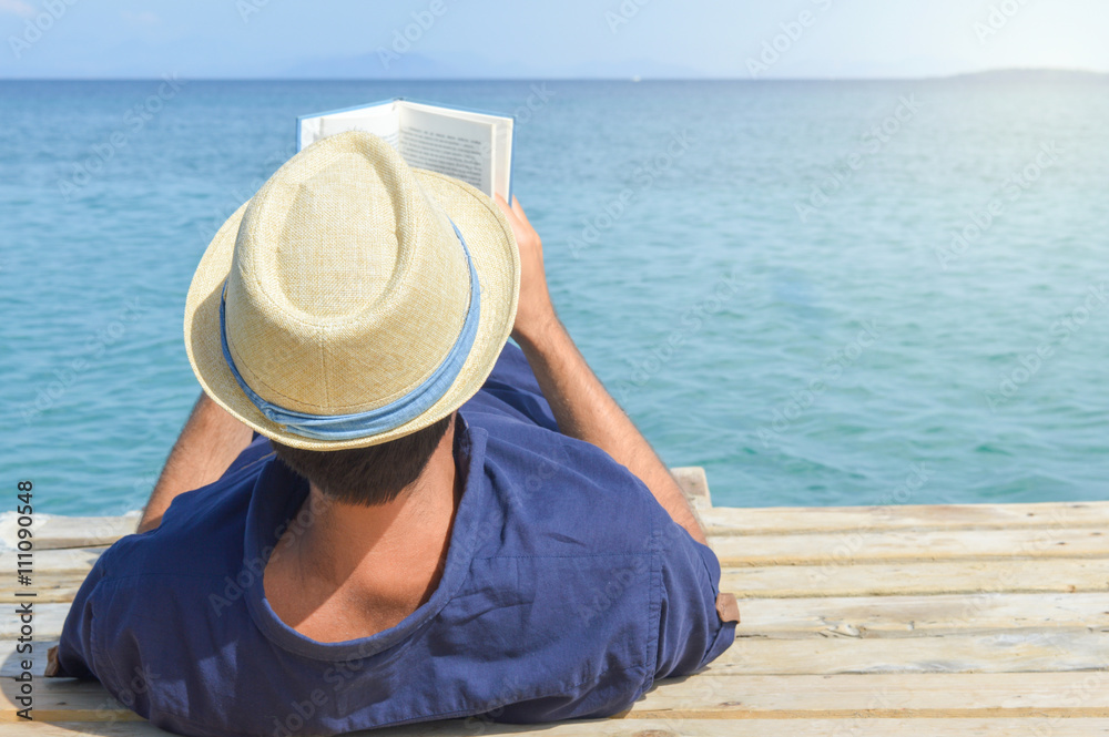 Man lying on the dock and reading a book