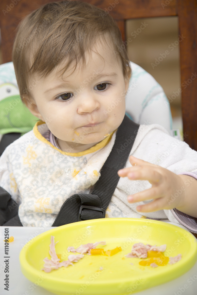 Baby looking away while sitting at table with plate Baby looking away while sitting at table with plate