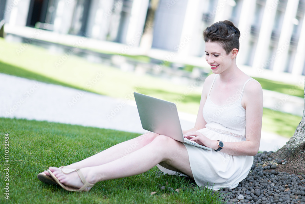 Young woman using tablet outdoor sitting on grass, smiling. Young woman using tablet outdoor sitting on grass, smiling.