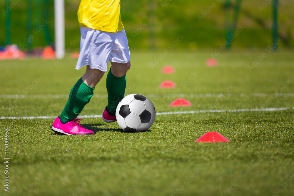 Boy kicking soccer ball on sports field. Soccer football training session for children