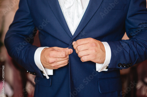 man buttoning a button on his jacket closeup