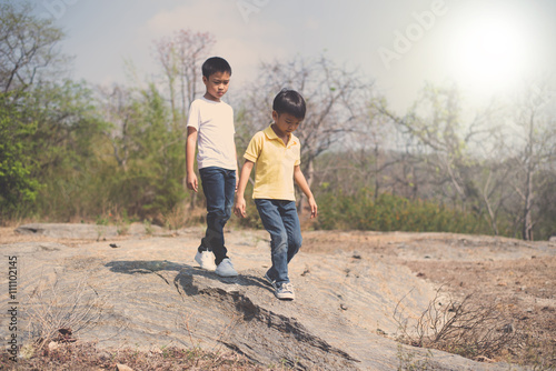 Two Boy walking on the rocky land.