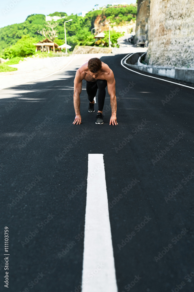 Athletics. Athletic Man With Fit Muscular Body In Starting Position For Running On Road. Handsome Runner Ready To Start Sprint Race. Fitness Model Training Outdoors In Summer. Sports Workout Concept