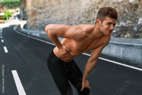 Stomach Ache. Closeup Portrait Of Athletic Man With Fit Muscular Body Touching Belly  Suffering From Abdominal Pain. Handsome Fitness Runner Feeling Bad After Running Outdoors. Sport Injury Concept
