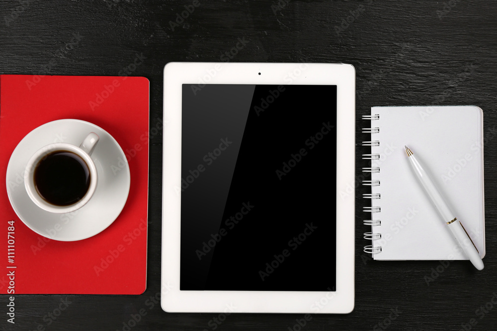 Digital tablet with cup of coffee and notebook on wooden table, closeup