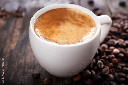 Cup of hot coffee with roasted beans on rustic wooden background
