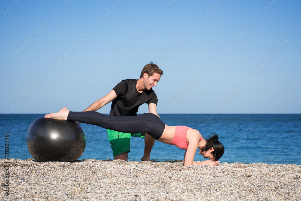 Sport und Fitness Instruktor zeigt junger Frau wie man mit Gymnastikball  den Rücken trainiert am Strand im Freien Stock Photo | Adobe Stock