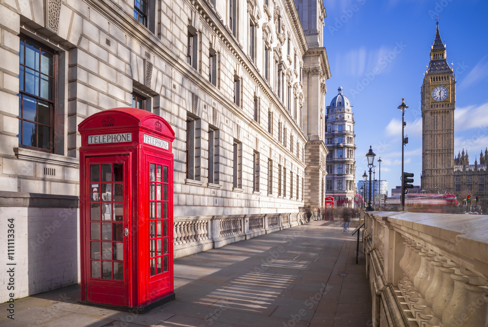 Obraz premium Tradycyjny czerwony brytyjski telefoniczny pudełko z Big Ben i Dwoistego Decker autobusem przy tłem na pogodnym popołudniu z niebieskim niebem i chmurami - Londyn, UK