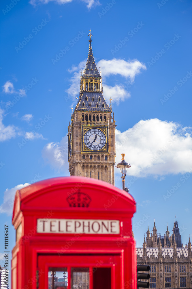 Obraz premium The Big Ben with traditional Red English telephone box in the foreground on a sunny afternoon with blue sky and clouds - London, UK