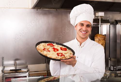 Male chef with Italian pizza at bistro.