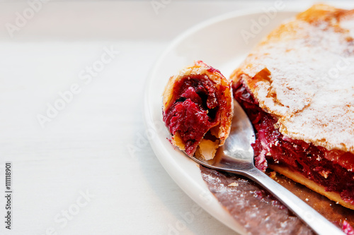 Cherry strudel on a saucer with a spoon. Piece of fresh tasty dessert with berries. © Konstantin Aksenov