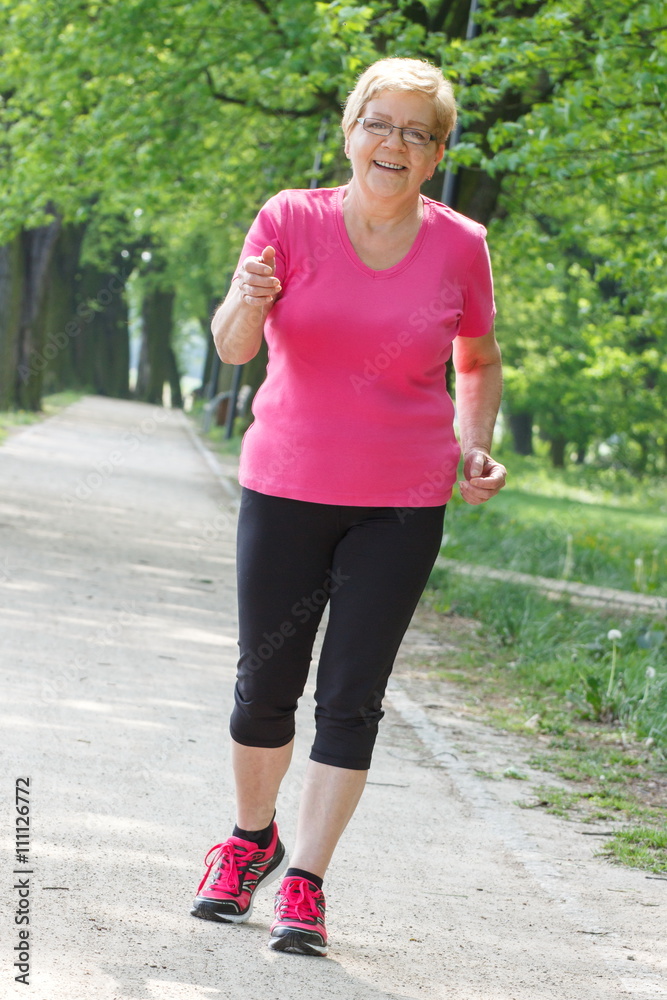 Senior woman running in sunny park, jogging outside, healthy lifestyle Senior woman running in sunny park, jogging outside, healthy lifestyle