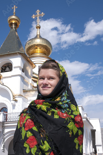 The girl in a scarf standing near a church