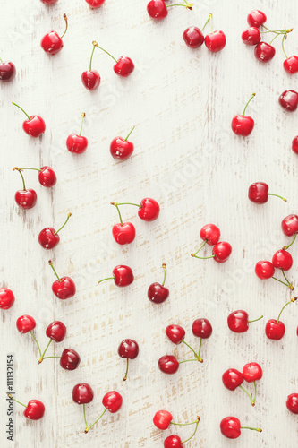 Cherry background. Red cherries scattered on rustic table. 