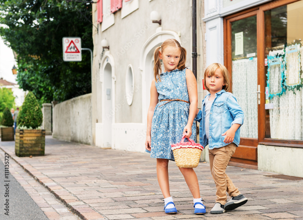 Portrait of fashion kids in a city, cute kids posing outdoors, adorable little girl and her brother wearing blue clothes