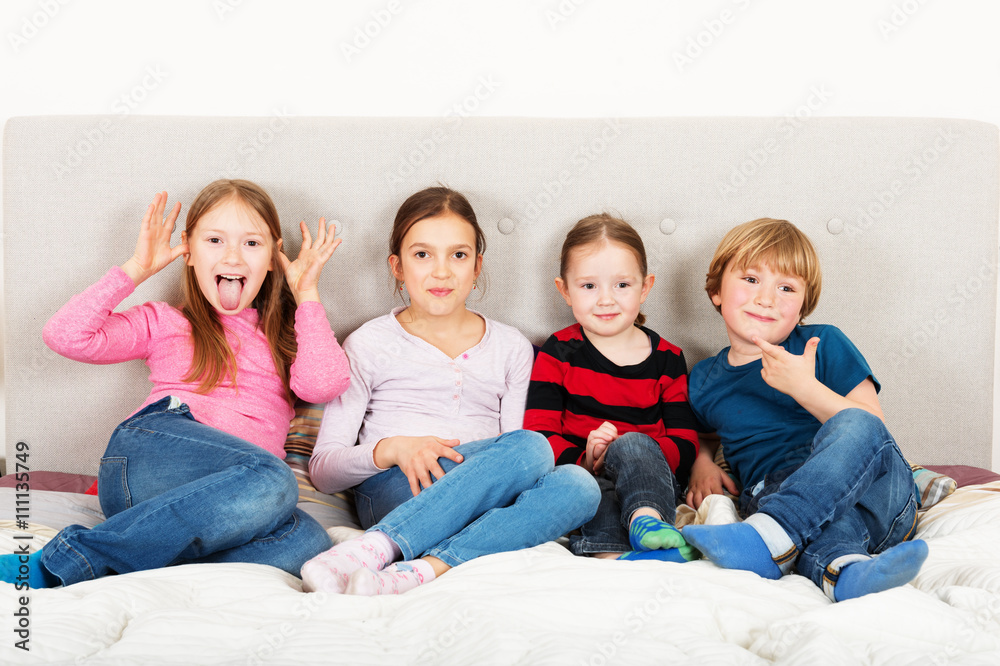 Group of 4 kids, three girls and one boy, playing on parent's bed