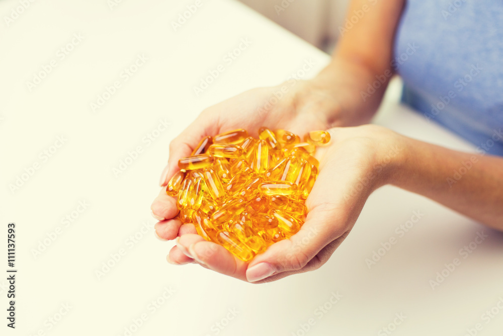 Obraz premium close up of woman hands holding pills or capsules