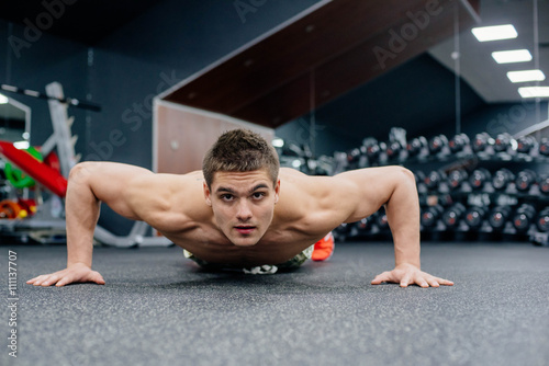 young muscular shirtless man doing exercises in gym