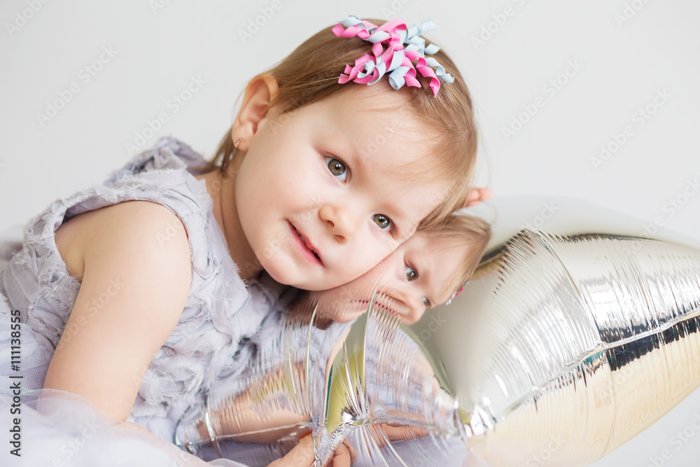 baby girl playing with silver star-shaped balloon. baby girl playing with silver star-shaped balloon.