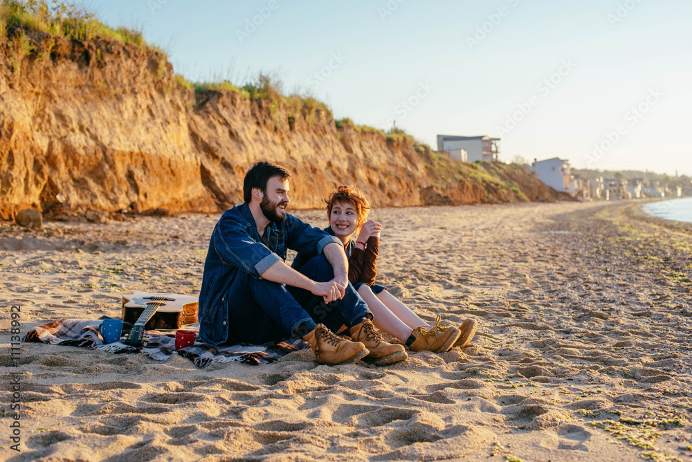 happy loving couple on beach, young man and woman enjoying sunset or sunrise on beach
