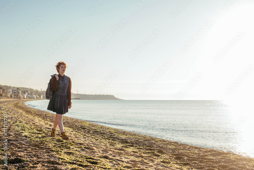 young caucasian redhead woman having fun on beach at sunset