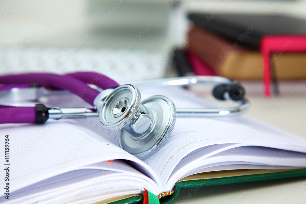 Stethoscope lying on a notebook computer in the background and books Stethoscope lying on a notebook computer in the background and books