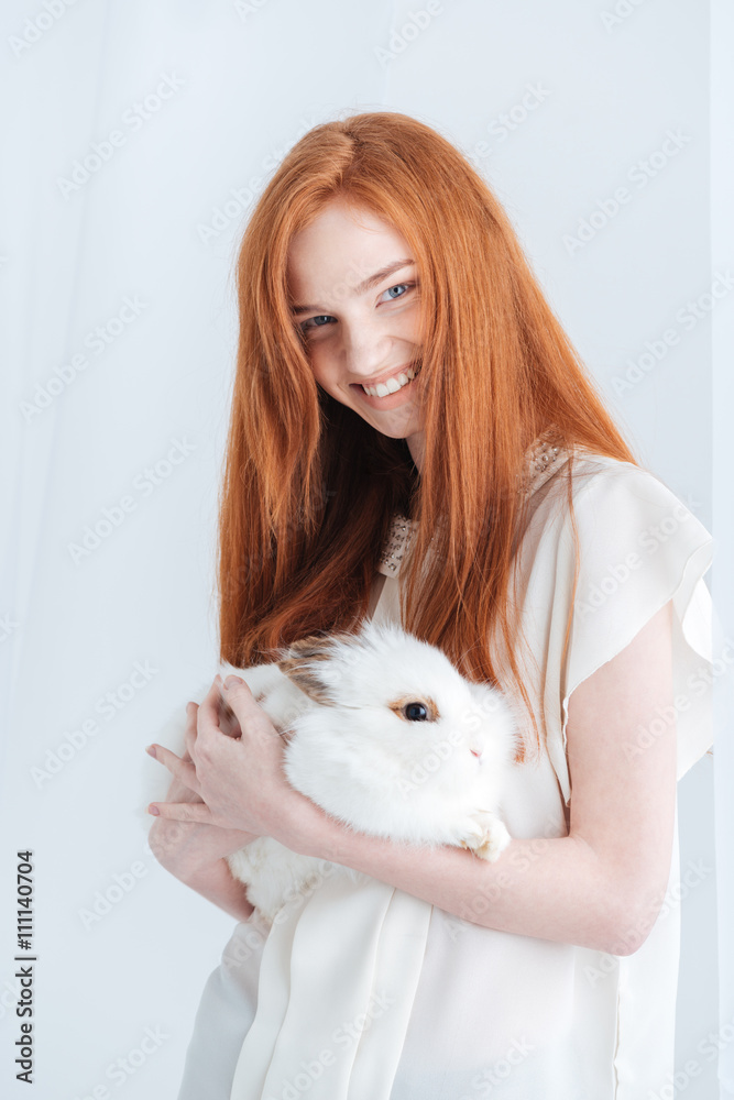 Smiling redhead woman holding rabbit Smiling redhead woman holding rabbit