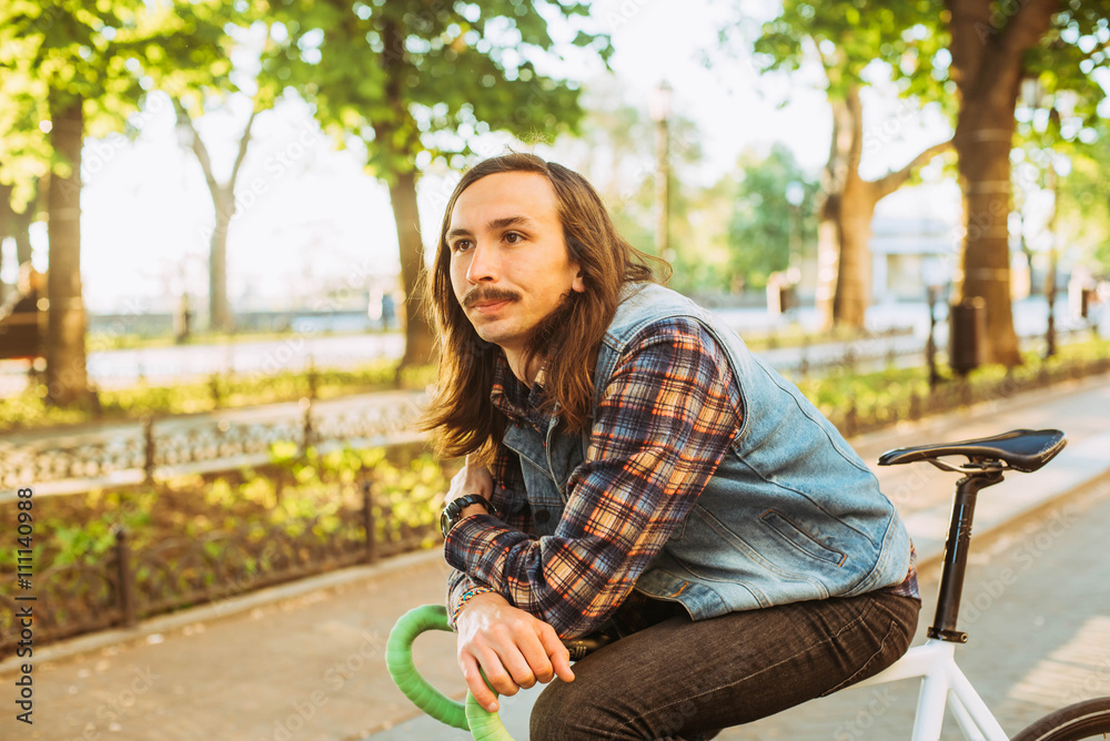 young brunette man riding fixed-gear bicycle in the city on a sunny day young brunette man riding fixed-gear bicycle in the city on a sunny day