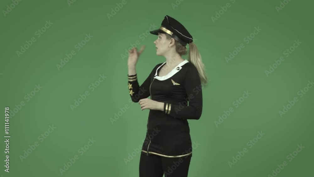 attractive caucasian air hostess isolated on green talking and pointing
