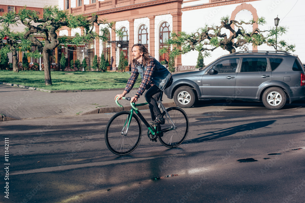 Fototapeta premium young brunette man riding fixed-gear bicycle in the city on a sunny day
