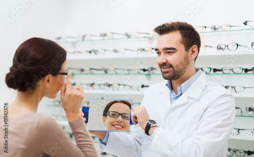woman in glasses looking to mirror at optics store