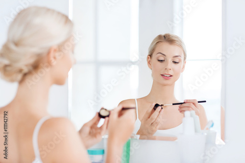 woman with makeup brush and eyeshade at bathroom