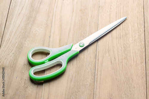green plastic scissor on wooden board
