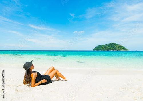 Tropical vacation. Young beautiful woman in black dress and hat on the beach. Thailand  Koh Lipe