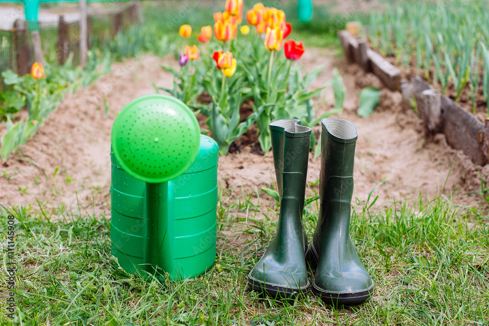 Rubber boots with watering can on grass Rubber boots with watering can on grass