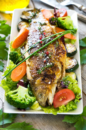 Grilled trout with vegetables on wooden background