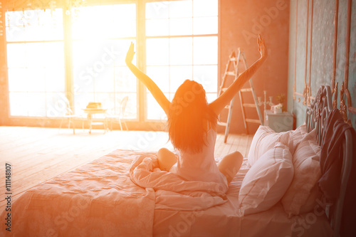 Woman stretching in bed after wake up photo